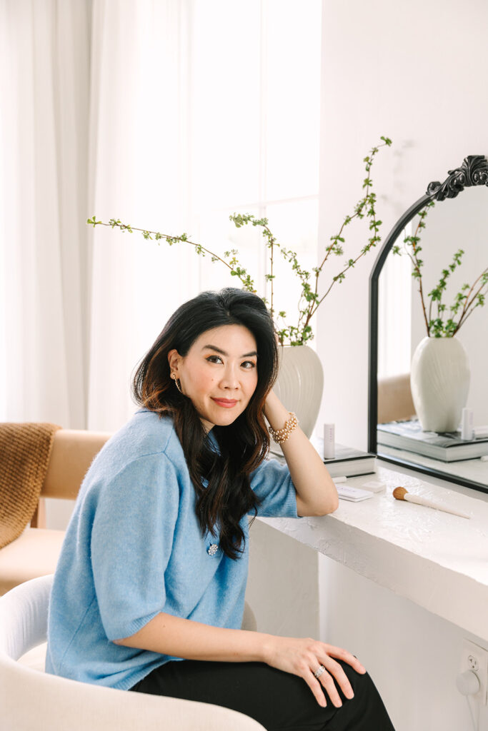 Beauty brand entrepreneur seated at a makeup vanity during a professional brand photoshoot.