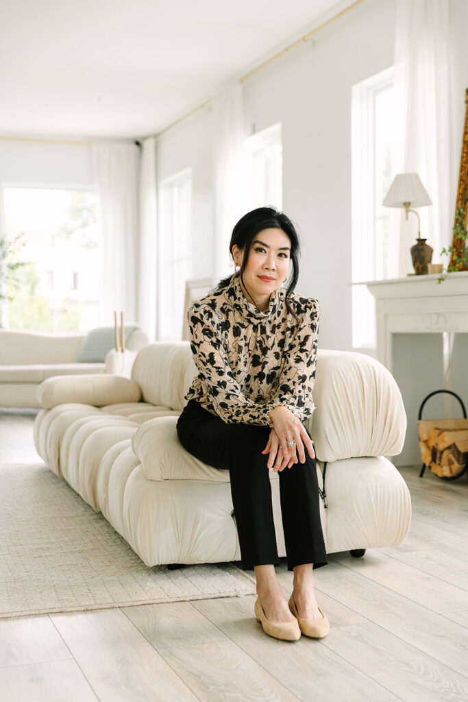 Female entrepreneur sitting on a modern couch in a floral blouse during a brand photoshoot.