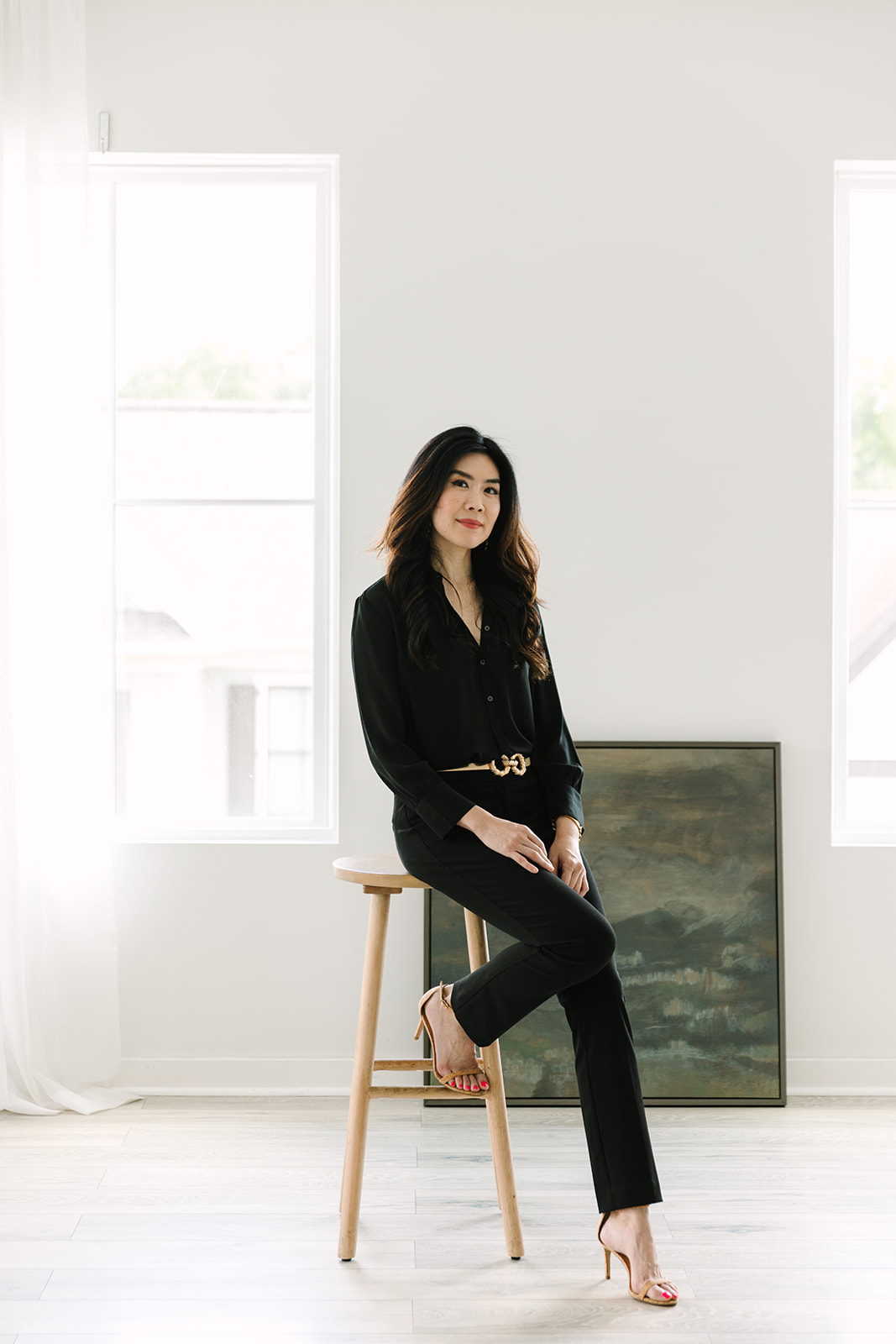 Female entrepreneur seated on a stool in a black suit, posed confidently during a brand photoshoot.