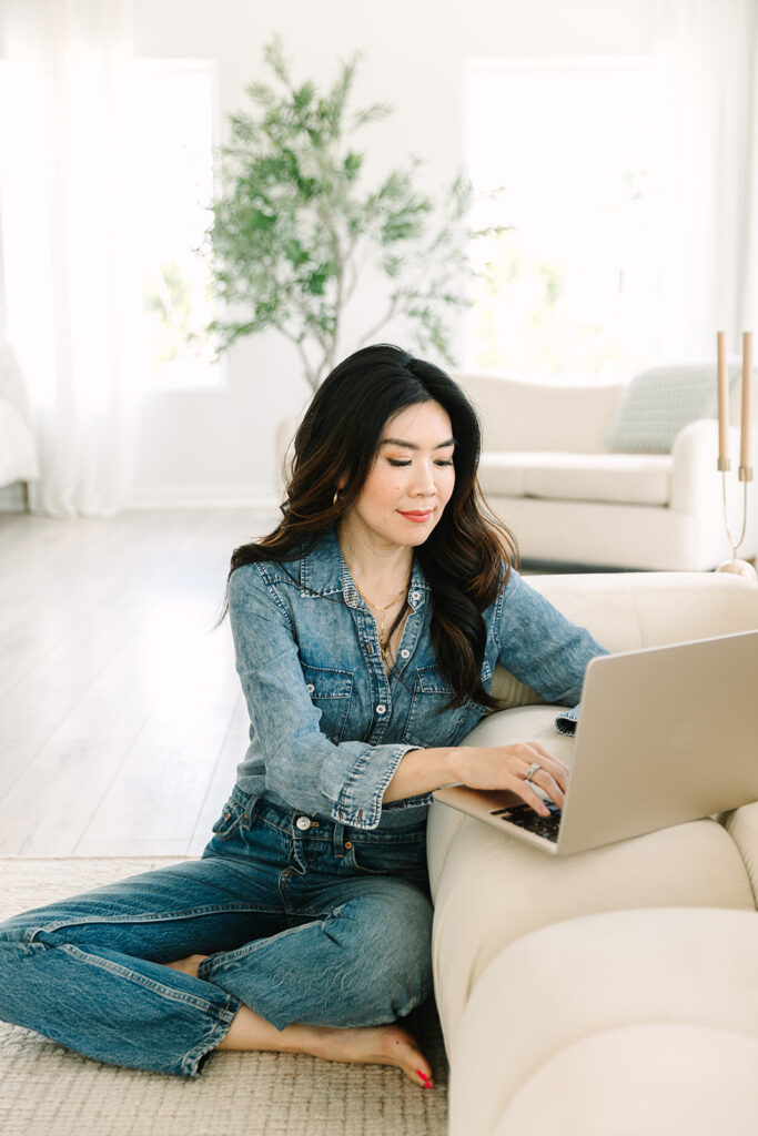 Entrepreneur working on her laptop while sitting comfortably on the floor in a modern living room.